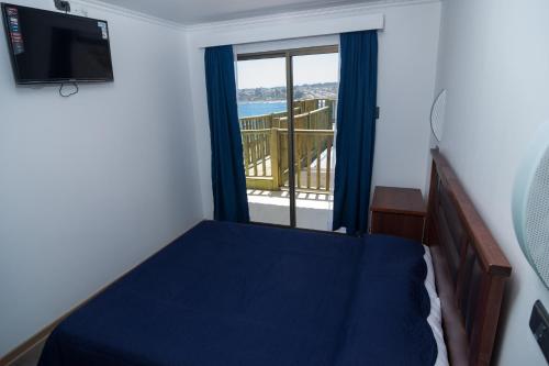 a bedroom with a bed and a window with a balcony at Altomiramar in El Quisco