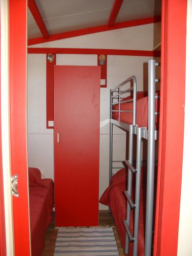 a bunk bed room with a red door and bunk beds at Parque de Campismo Orbitur Montargil in Montargil