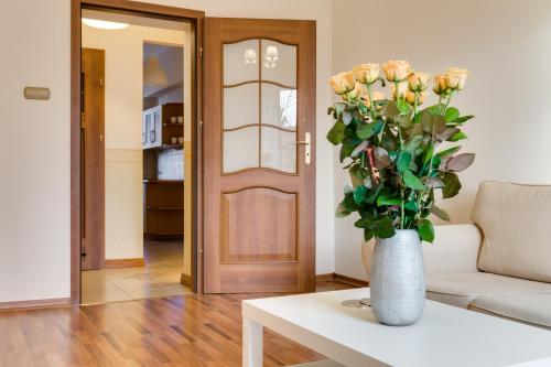 a vase of flowers on a table in a living room at Elite Apartments Korzenna City Center in Gdańsk