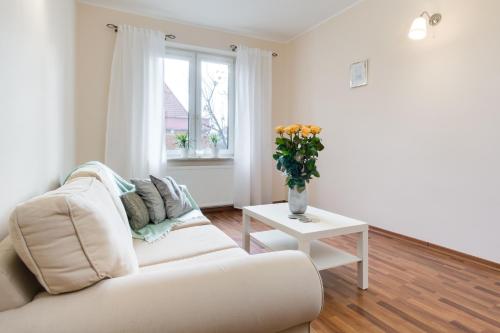 a white living room with a white couch and a vase of flowers at Elite Apartments Korzenna City Center in Gdańsk