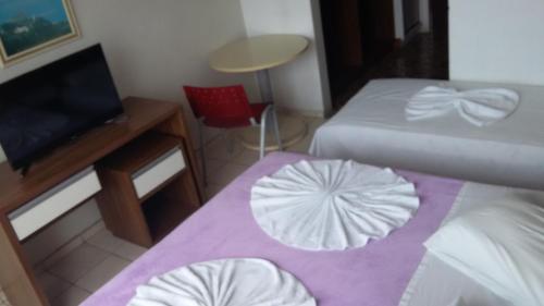 a small room with two beds and a table and a chair at Hotel Monte Líbano in Laguna