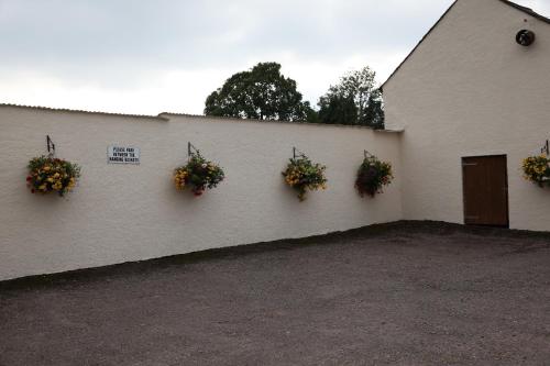 a white building with flower boxes on a wall at Weir Mill Farm in Cullompton