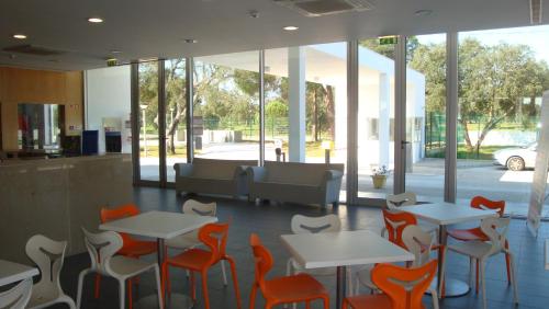 ein Restaurant mit orangefarbenen und weißen Tischen und Stühlen in der Unterkunft Parque de Campismo Orbitur Montargil in Montargil