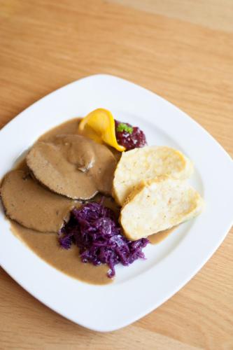 a white plate of food on a wooden table at Gasthof Pension Zoller in Wolfsberg