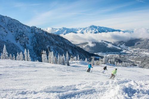 three people are skiing down a snow covered mountain at Landhaus Almidyll in Seefeld in Tirol