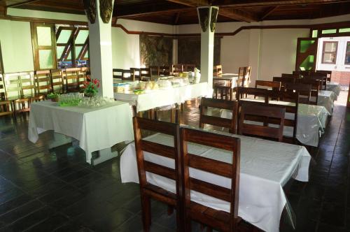 a restaurant with white tables and chairs and tablesearcher at Pousada Do Bosque in Itajuípe