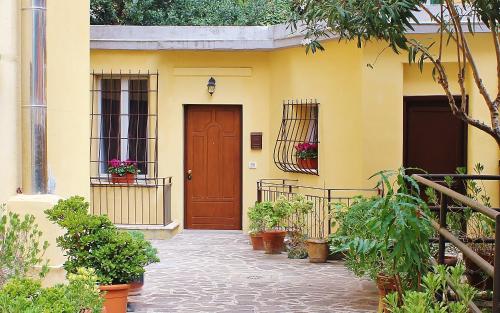 a yellow house with a brown door and potted plants at Alfieri home holiday in Rome