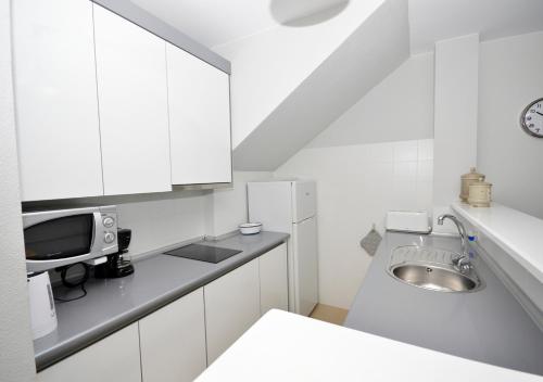 cocina blanca con fregadero y microondas en Apartamento Mariposa, en Conil de la Frontera