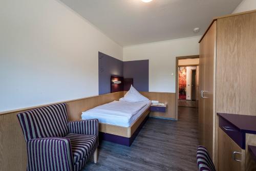 a hotel room with a bed and a chair at Kloster Neustadt in Neustadt an der Weinstraße