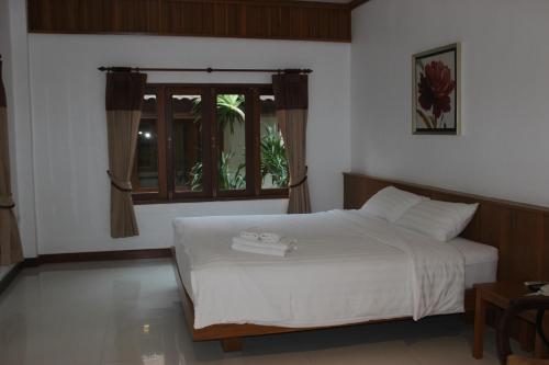 a bedroom with a white bed and a window at Tree Home Plus in Nakhon Si Thammarat