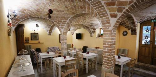 a restaurant with white tables and chairs and a brick wall at Donna Matilde in Pescocostanzo