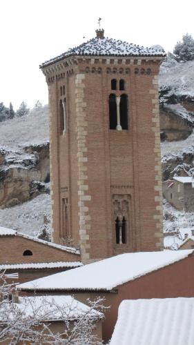a brick clock tower with snow on the ground at Posada del Almudí in Daroca