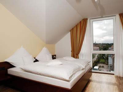 a white bed in a room with a large window at AKZENT Hotel Altenberge in Altenberge