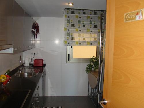 uma pequena cozinha com um lavatório e uma janela em Apartamento Playa Esquirol em Cambrils