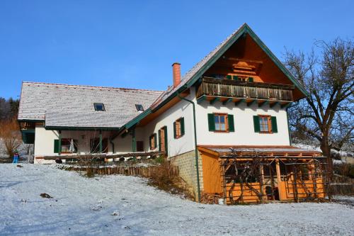 a large wooden house with a balcony in the snow at Bauernhof Grain in Feldbach