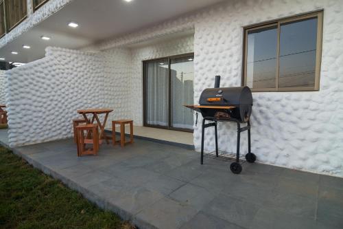a grill on a patio with a table and chairs at Altomiramar in El Quisco