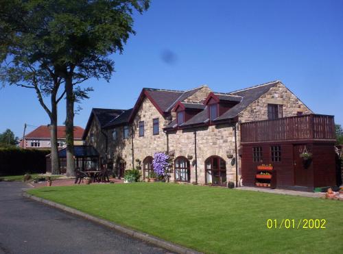 a large stone house with a grass yard at Stone Cottage in Ponteland