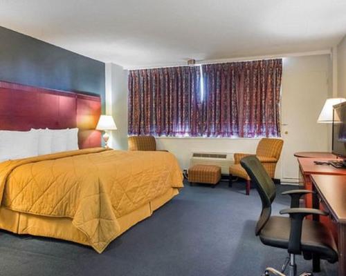 a hotel room with a bed and a desk at Econolodge Smiths Falls in Smiths Falls