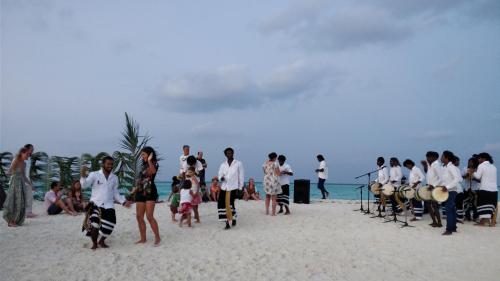 a group of people on a beach playing drums at Holiday Haven Ukulhas in Ukulhas
