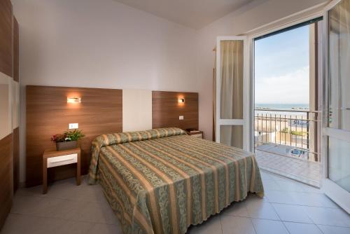 リド・ディ・サヴィオにあるHotel Vallechiaraのベッドとバルコニー付きのホテルルーム