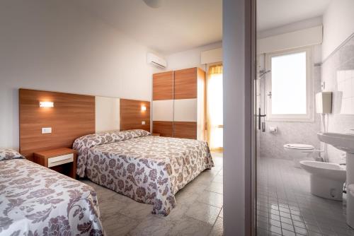 リド・ディ・サヴィオにあるHotel Vallechiaraのベッド2台とバスルームが備わるホテルルームです。