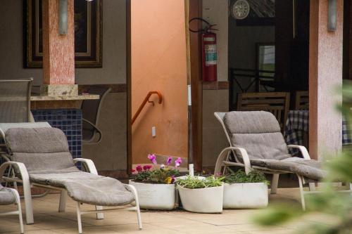 two chairs and flowers in pots on a patio at Pousada Doce Vida Guarapari in Guarapari