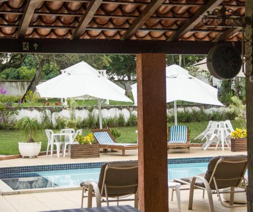 a swimming pool with chairs and umbrellas next to a pool at Pousada Doce Vida Guarapari in Guarapari