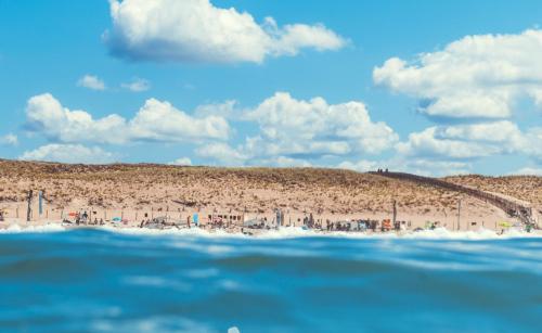 a beach with a group of people on the sand at Single Fin Hotel & Lodge in Mimizan-Plage
