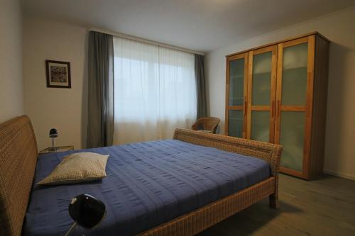 a bedroom with a bed with a blue sheets and a window at City-Apartment - Lüneburg Schwalbengasse in Lüneburg