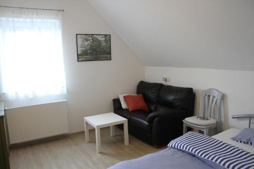 a living room with a black couch and a bed at Ferienwohnung I in Schnelldorf