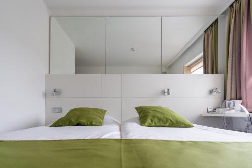 een slaapkamer met een bed met groene kussens bij Hotel Expo in Brussel