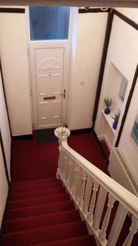 a stairway with a white door and red carpet at The Coach House Apartment in Lytham St Annes