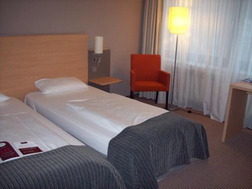 a hotel room with a bed and a chair at Mercure Hotel Düsseldorf Neuss in Neuss