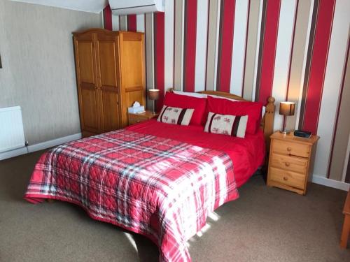 a bedroom with a red bed with a red and white blanket at Nether Onston Cottage in Stenness