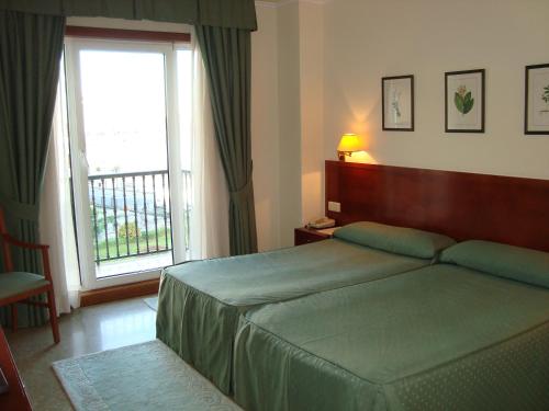 sypialnia z łóżkiem i dużym oknem w obiekcie Hotel Bahía Bayona w mieście Baiona