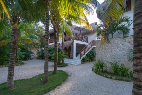 a house with palm trees in front of it at Prana Boutique Hotel Tulum in Tulum