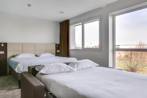 two beds in a room with two windows at The Originals City, Hôtel Caen Mémorial in Caen