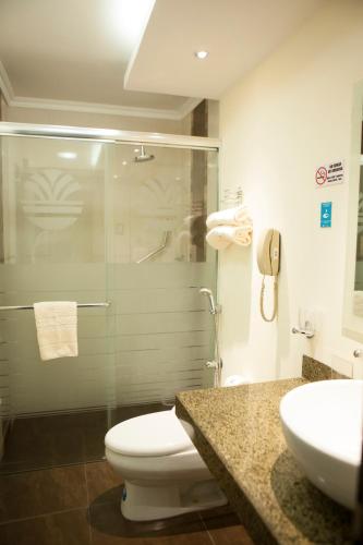 a bathroom with a toilet and a glass shower at Hotel Ramada in Guayaquil