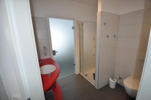 W łazience znajduje się czerwona toaleta i umywalka. w obiekcie Apartment NewPort Bremerhaven w mieście Bremerhaven
