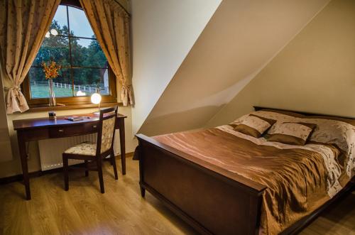 a bedroom with a bed and a desk and a window at Pensjonat Enklawa in Trzebnica