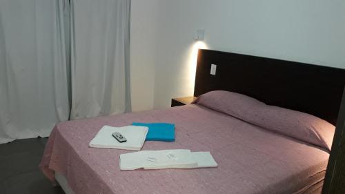 a bedroom with a pink bed with two towels on it at Akun Hotel in Santa Clara del Mar