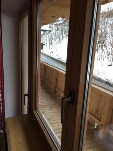 a door with a view of a balcony with snow at Brenners Dorfstube in Fieberbrunn