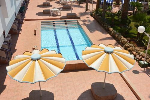 a pool with two umbrellas in front of it at Residence Yasmina Agadir in Agadir