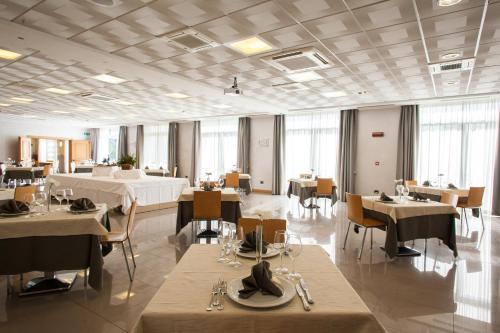 Palace Hotel Zingonia في فيرديلّينو: غرفة طعام مع طاولات وكراسي ونوافذ