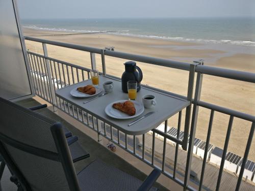 オーステンデにあるZeedijk Mariakerkeのビーチ沿いのバルコニーにテーブルと飲食物