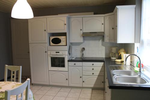 a kitchen with white cabinets and a sink at Au coeur de l'Alsace in Eschau