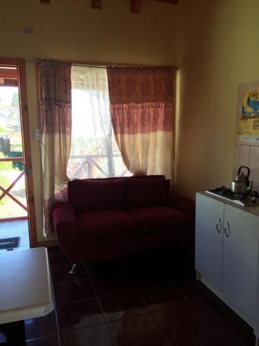 a living room with a red couch in front of a window at Cabañas Las Palmeras Pichilemu in Pichilemu