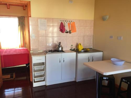 a small kitchen with white cabinets and a table at Cabañas Las Palmeras Pichilemu in Pichilemu