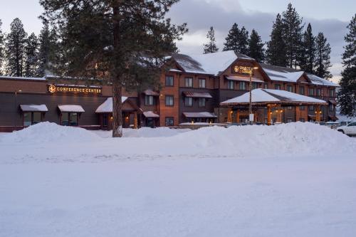 a large building with snow in front of it at Cedar Creek Lodge & Conference Center in Columbia Falls