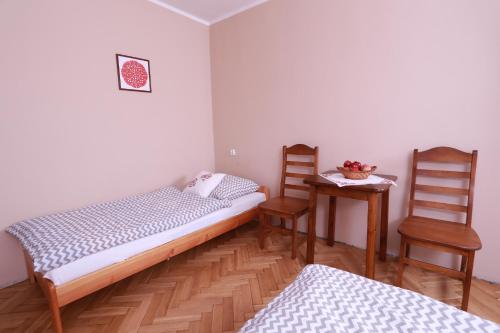 a bedroom with two beds and a table and two chairs at Willa Bona blisko Zamku Królewskiego i Rezerwatu Rzepka in Chęciny
